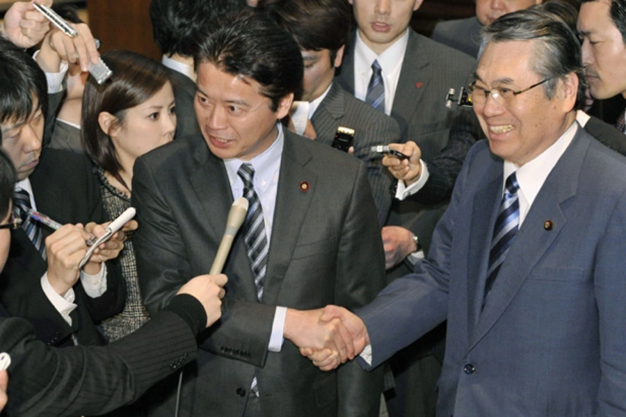 Japan's Foreign Minister Koichiro Gemba shakes hands with Defence Minister Naoki Tanaka as they are surrounded by media in Tokyo