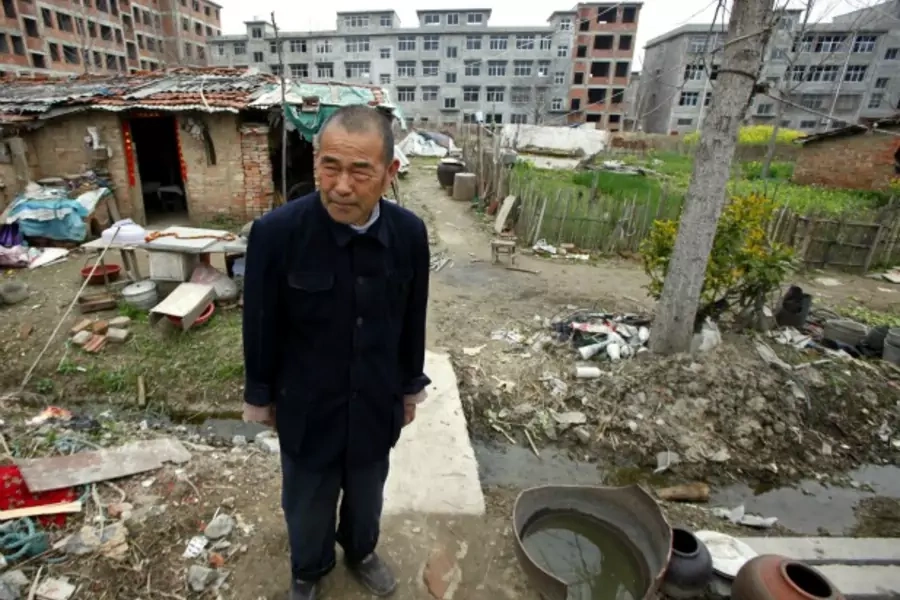 Farmer Xiang Wen Jiang stands in front of his house, surrounded by newly constructed residential buildings in the town of Gushi, Henan Province on March 28, 2010.
