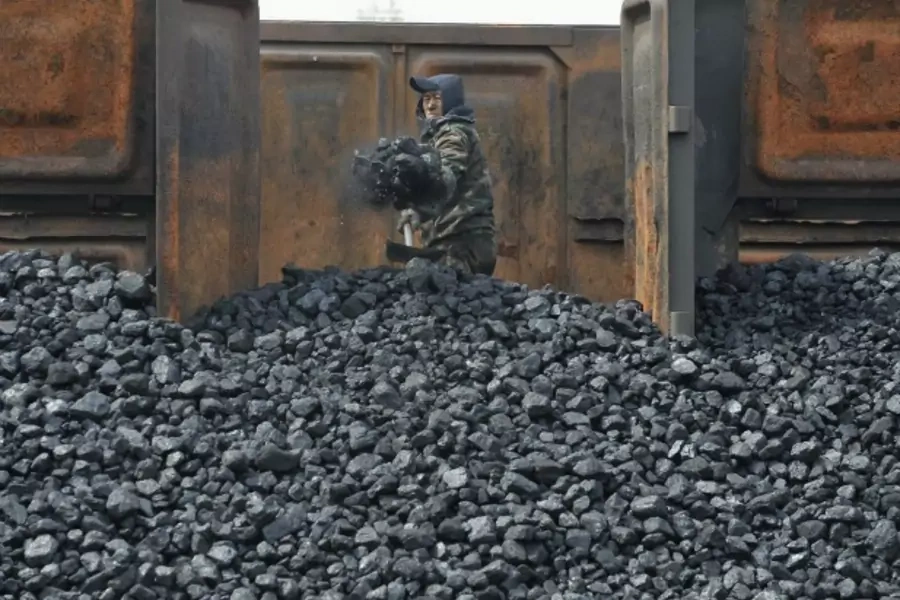 A worker unloads coal at a storage site along a railway station in Shenyang, Liaoning province on April 13, 2010.