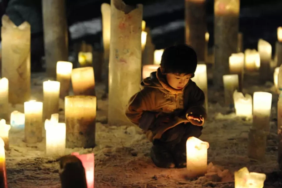 A child looks at a candle flame during an event to pray for the reconstruction of areas devastated by the March 11, 2011 earthquake and tsunami, in Iwanuma in Miyagi prefecture.