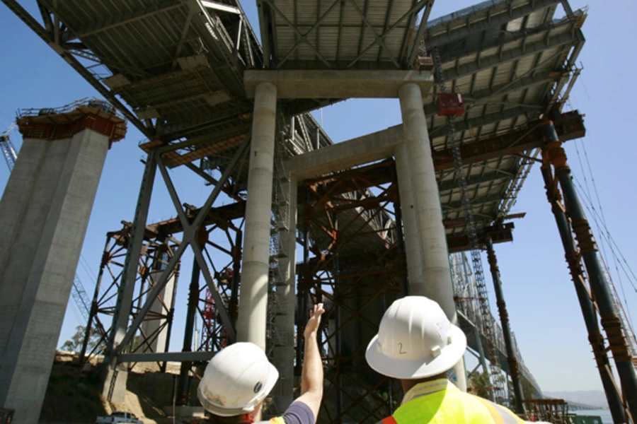 A worker displays a new section of roadway on the San Francisco Bay Bridge (Robert Galbraith/Courtesy Reuters).