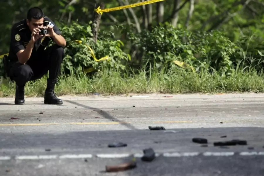 A policeman takes photos at the scene of a deadly shootout near Zacapa, Guatemala (Courtesy Reuters/Daniel Leclair).