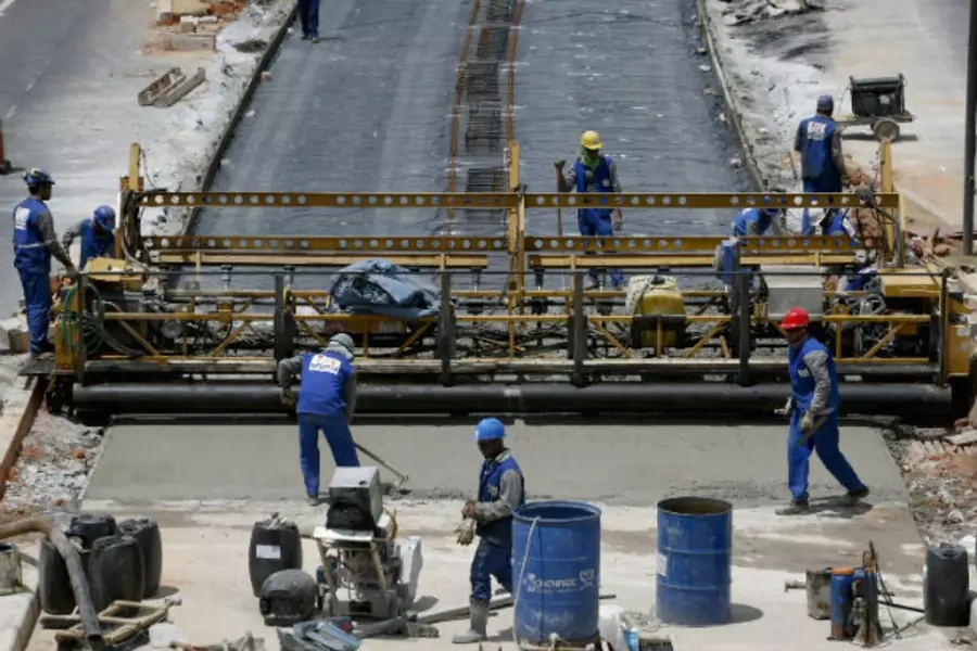 Workers spread cement for a new bus lane projected to carry more passengers during the 2014 World Cup, in Belo Horizonte