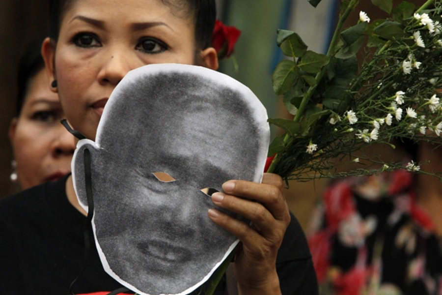 An activist holds a cut-out mask of Amphon Tangnoppaku outside Bangkok Remand Prison.