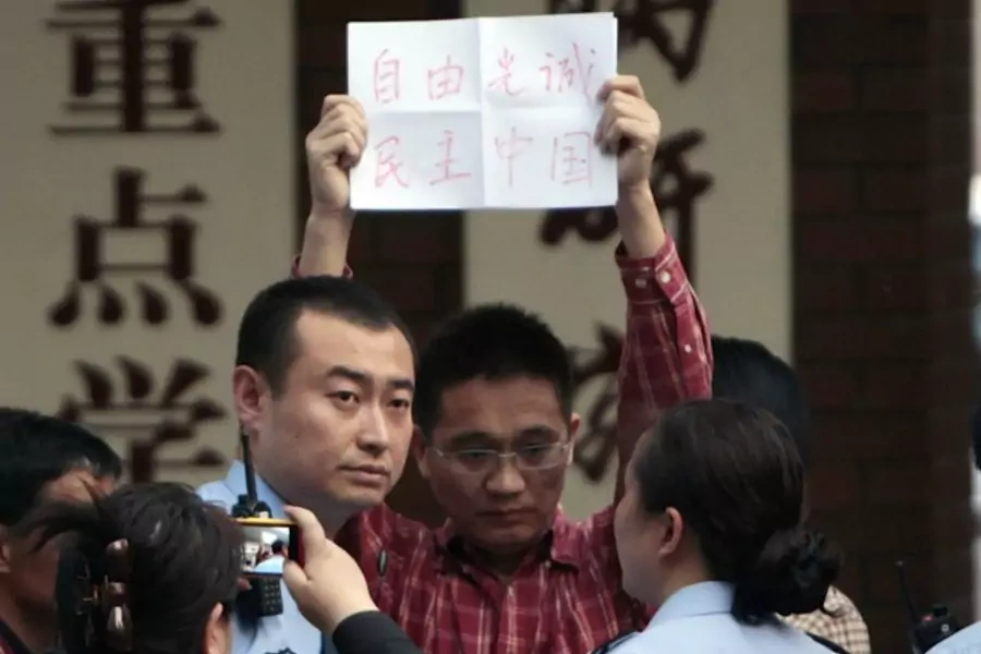 A supporter of Chen Guangcheng holds up a piece of paper reading, "Freedom, Guangcheng, Democracy, China", as he is being take...lice officers at Chaoyang Hospital in Beijing, where blind activist Chen Guangcheng was reported to be staying on May 2, 2012.