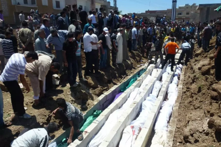 People gather around a mass burial for victims purportedly killed at the massacre in the Syrian village of Houla on May 25. (Courtesy Reuters)