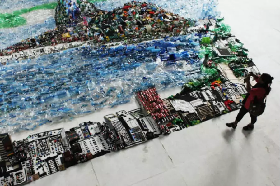 A woman takes a picture of an image of Guanabara Bay made of recycled trash, part of an installation by Brazilian plastic artist Vik Muniz, during the Rio+20 Conference on June 22, 2012 (Nacho Doce/Courtesy Reuters).
