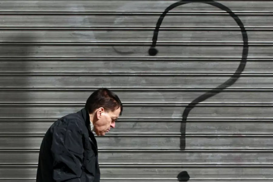 A man walks in front of a closed bank branch in central Athens, February 2012 (John Kolesidis/Courtesy Reuters).
