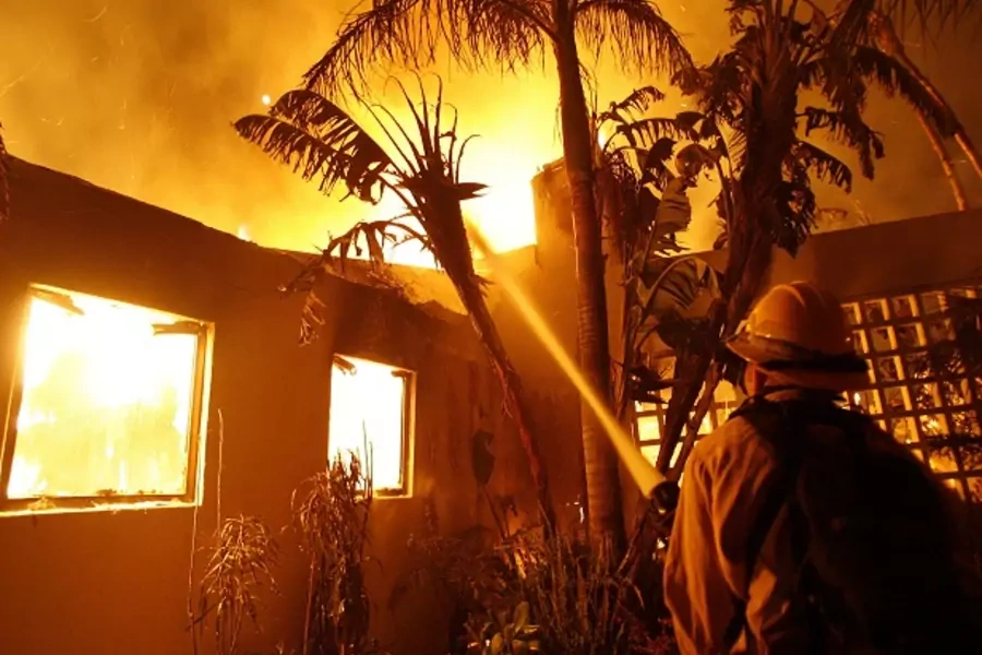 A firefighter sprays water on a burning house in Santa Barbara, California (Mario Anzuoni/Courtesy Reuters).