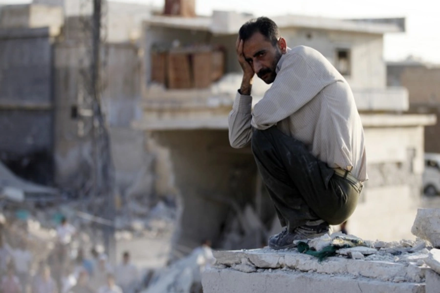 A man sits in front of houses destroyed during a recent air strike in Azaz, Syria (Goran Tomasevic/Courtesy Reuters).