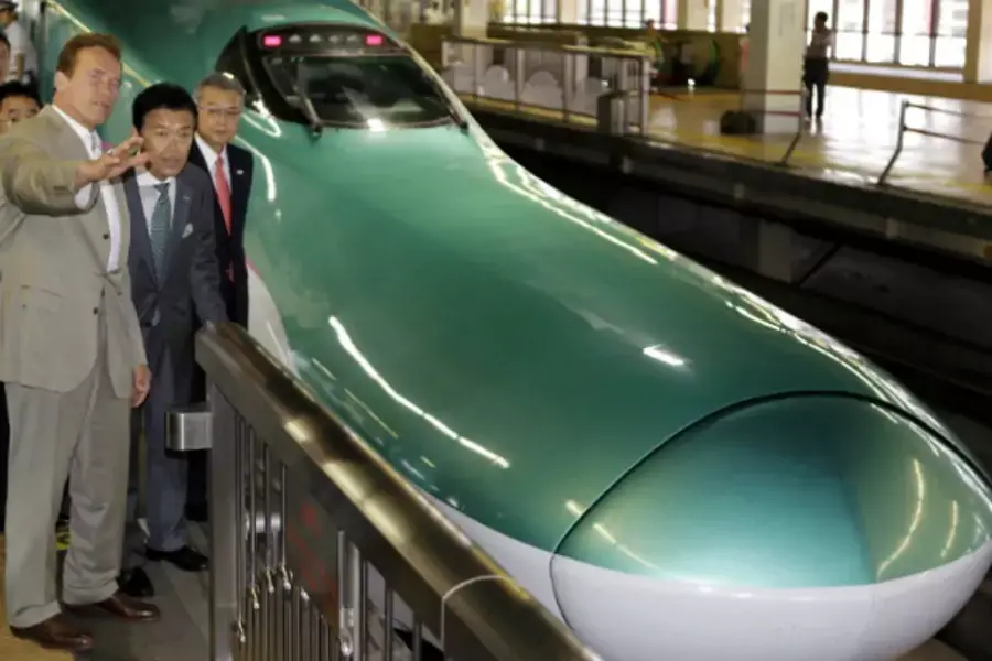 East Japan Railway’s Vice President and Arnold Schwarzenegger stand near a bullet train during a tour of Japan’s high speed train operations in September 2010 (Pool/Courtesy Reuters).