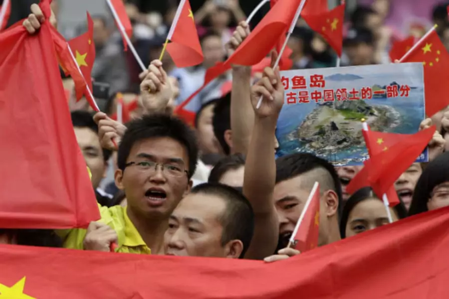 Protesters hold Chinese national flags and a poster showing the disputed Islands, called Senkaku by Japan and Diaoyu by China, on the 81st anniversary of Japan's invasion of China, in Chengdu.