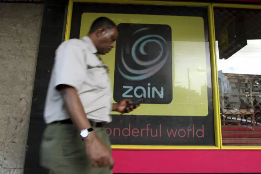 A man uses his mobile phone as he walks past a Zain customer care shop in Nairobi on February 15, 2010 (Thomas Mukoya/Courtesy Reuters).