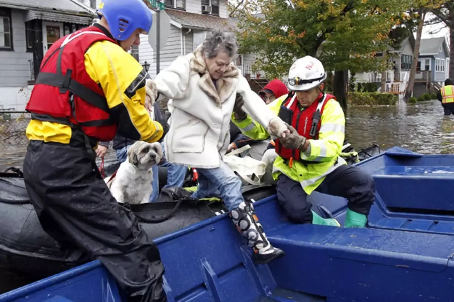 Emergency personnel help a resident onto a boat after rescuing her from flood waters brought on by Hurricane Sandy in Little Ferry, New Jersey on October 30, 2012 (Adam Hunger/Courtesy Reuters).