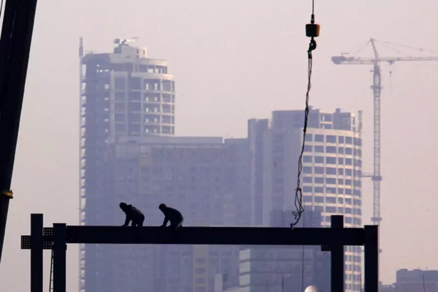 Workers crawl along a steel pylon on top of a building under construction in central Beijing (David Gray/Courtesy Reuters).