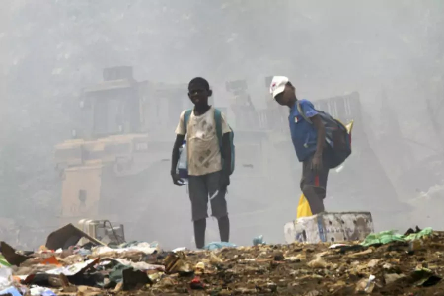 Children stand on garbage as they scavenge at a public dump in Malabo, Equatorial Guinea on January 28, 2012 (Luc Gnago/Courtesy Reuters).
