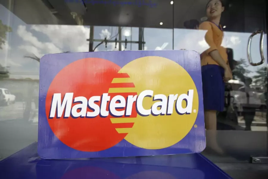 An employee stands behind a MasterCard logo during the launch of the international credit card issuer's first ATM transaction in Myanmar, in Yangon November 15, 2012.