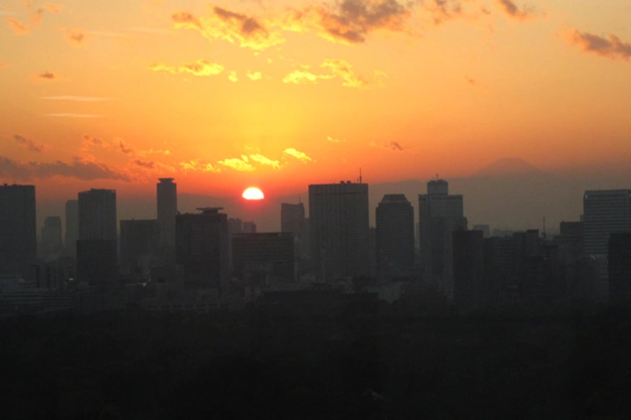 Buildings are silhouetted against the setting sun in front of Mount Fuji in Tokyo