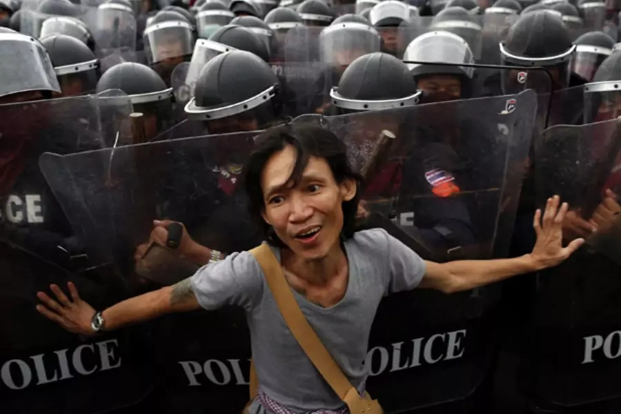 An anti-government protester pushes riot police officers during scuffles near the Government house in Bangkok November 24, 2012.