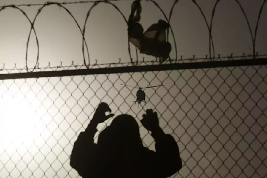A man watches a U.S. border patrol helicopter from a fence at the border in Ciudad Juarez (Stringer Mexico/Courtesy Reuters).