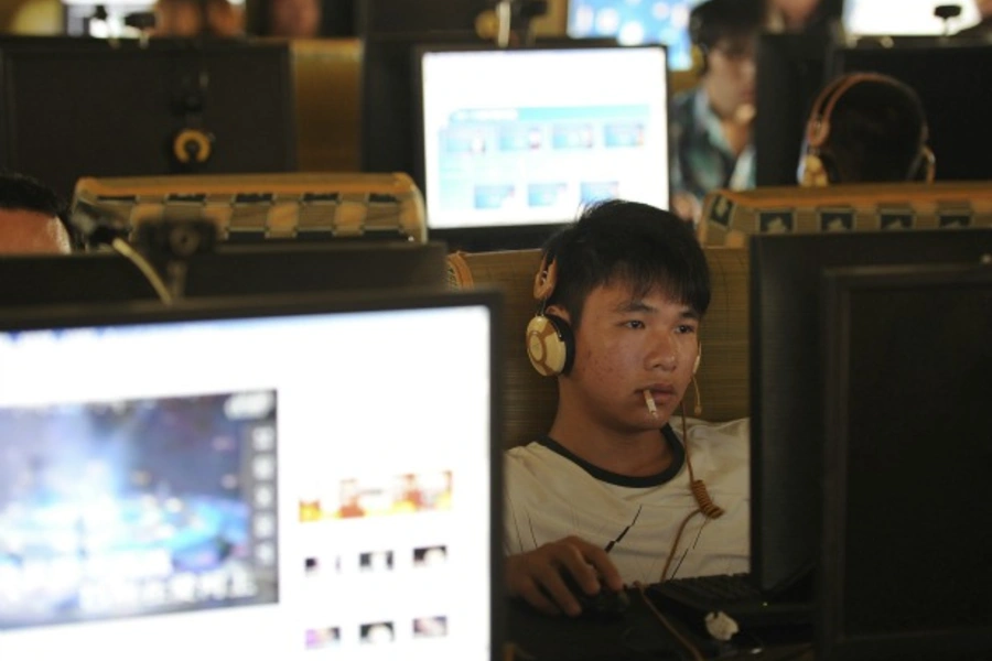 A man smokes as he uses a computer at an internet cafe in Hefei, Anhui province,