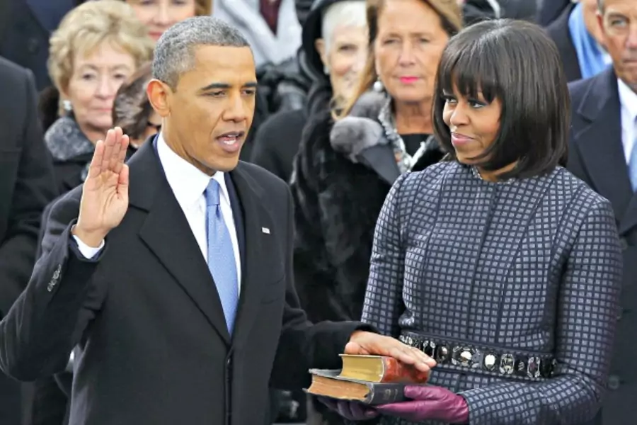 U.S. President Barack Obama recites his oath of office as first lady Michelle Obama looks on during swearing-in ceremonies on the West front of the U.S Capitol in Washington, DC, on January 21, 2013.