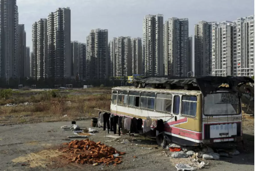 Clothes are seen hanging outside a bus which has been converted into a dwelling for Lu Changshan and his wife, near newly-constructed residential buildings in Hefei, Anhui province on November 12, 2012 (Jianan Lu/Courtesy Reuters).