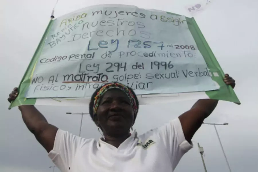 A woman holds a banner during a protest against all forms of violence calling for respect for the rights of women, in Cartagena, Colombia on July 5, 2012 (Joaquin Sarimento/Courtesy Reuters).