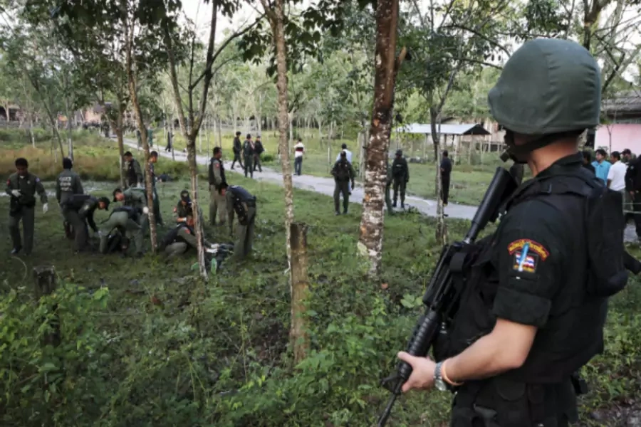 Security personnel investigate around bodies of insurgents at the site of an attack on an army base in the troubled southern province of Narathiwat February 13, 2013.