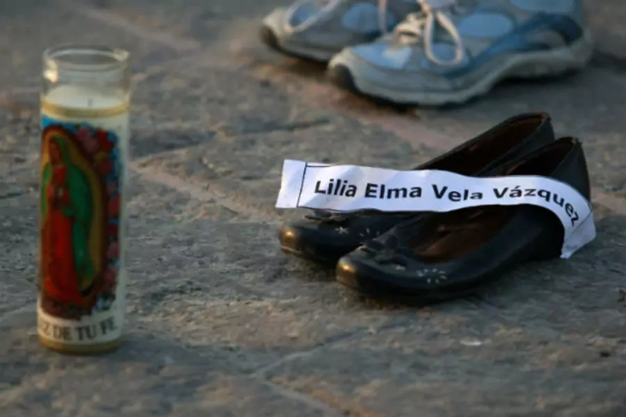 A candle and a pair of shoes with a name tag of its owner, a victim of the drug war, are arranged at a square in Monterrey January 15, 2012.