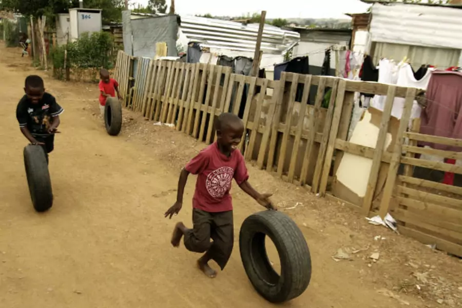 Young boys play with car tyres in a township outside Johannesburg on January 25,2009 (Siphiwe Sibeko/Courtesy Reuters).