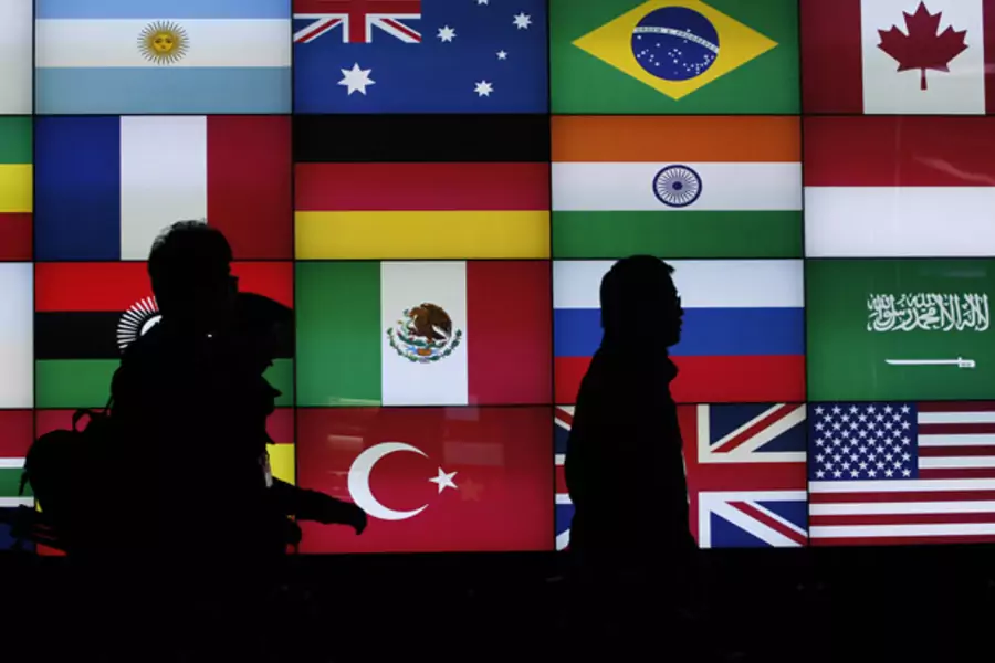 Media workers walk past a screen showing flags of the participating countries during the G20 summit in Seoul, South Korea (Jo Yon-Hak/Courtesy Reuters).