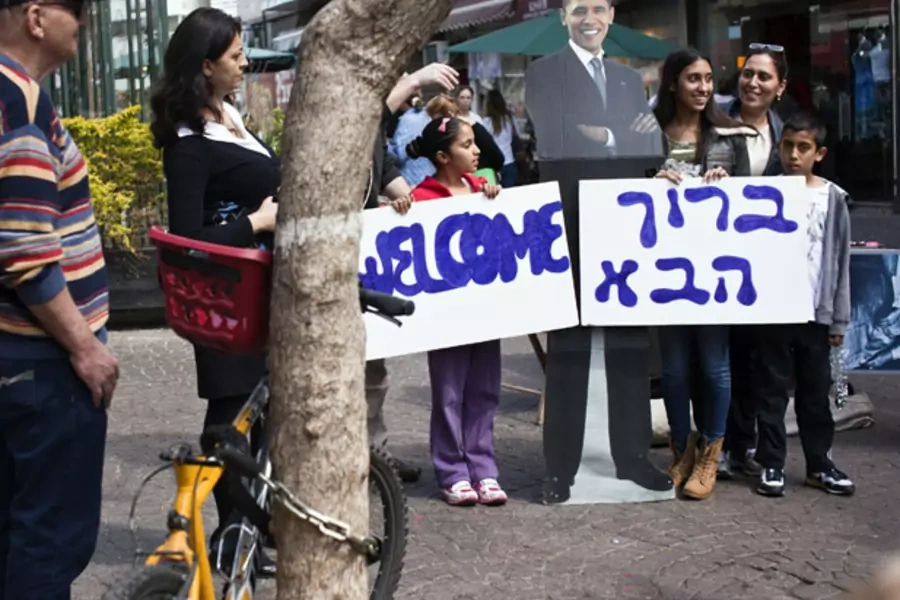 An Israeli family holds welcome signs in Hebrew and English during an event organized by the U.S. embassy in Tel Aviv on March 1, 2013 (Nir Elias/Courtesy Reuters).