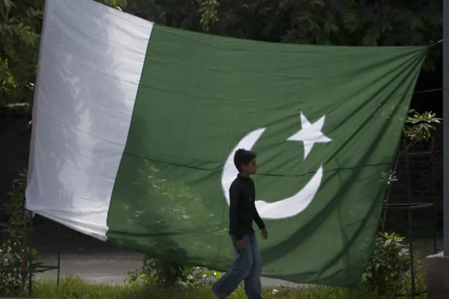 A boy walks past a Pakistani flag in Rawalpindi (Faisal Mahmood/Courtesy Reuters).