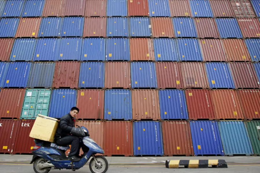A man rides his motorcycle past shipping containers at the Port of Shanghai (Aly Song/Courtesy Reuters).