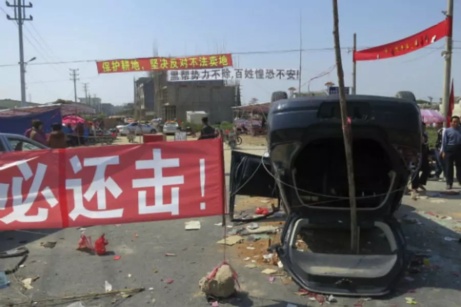 DATE IMPORTED:March 7, 2013A red sign "We must retaliate" is displayed next to an upended car at the entrance of Shangpu village, in China's southern Guangdong province on March 5, 2013 (James Pomfret/Courtesy Reuters).