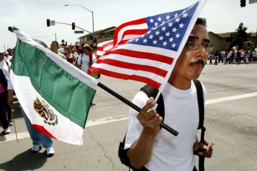 A worker carries the flags of Mexico and the U.S. during a march through the streets of Salinas, California May 1, 2006 (Robert Galbraith/Courtesy Reuters).
