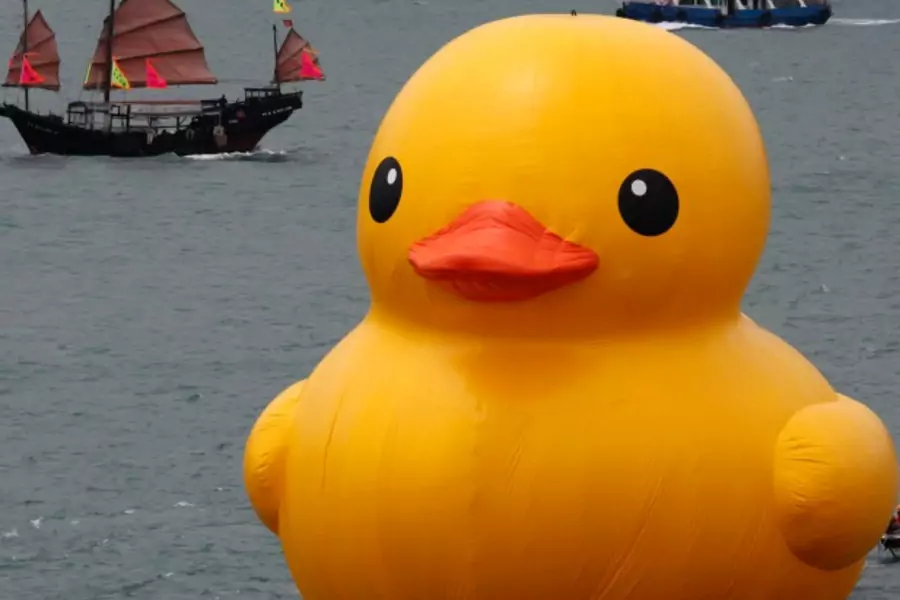 A traditional Chinese tourist junk sails past Rubber Duck by Dutch conceptual artist Florentijn Hofman at Hong Kong's Victoria Harbour on May 2, 2013. (Bobby Yip/Courtesy Reuters)