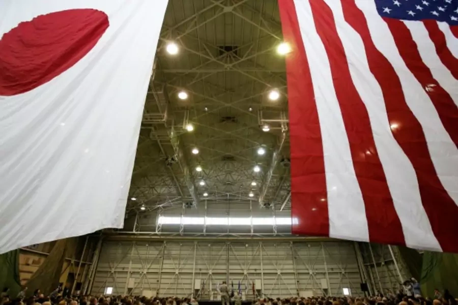 U.S. Chairman of the Joint Chiefs of Staff Army Gen. Martin Dempsey (centre R) stands below flags of Japan (L) and the U.S. as he talks to U.S. military personnel stationed at Yokota Air Base in Tokyo on April 25, 2013. (Courtesy Reuters/Yuya Shino)