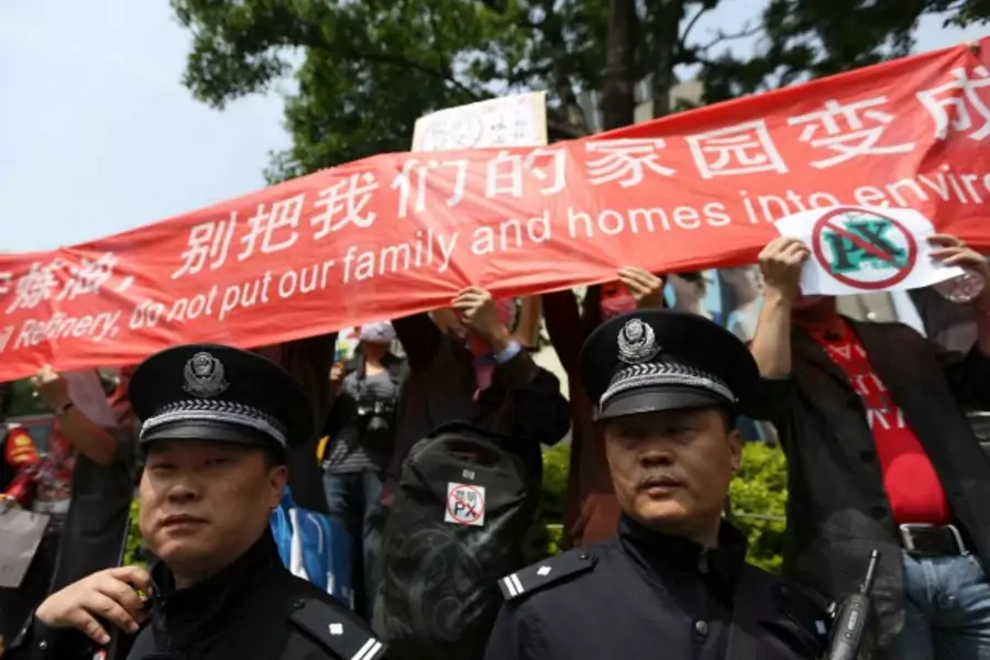 Police officers stand guard as residents raise a banner to protest against a planned refinery in Kunming, Yunnan province, on May 4, 2013.