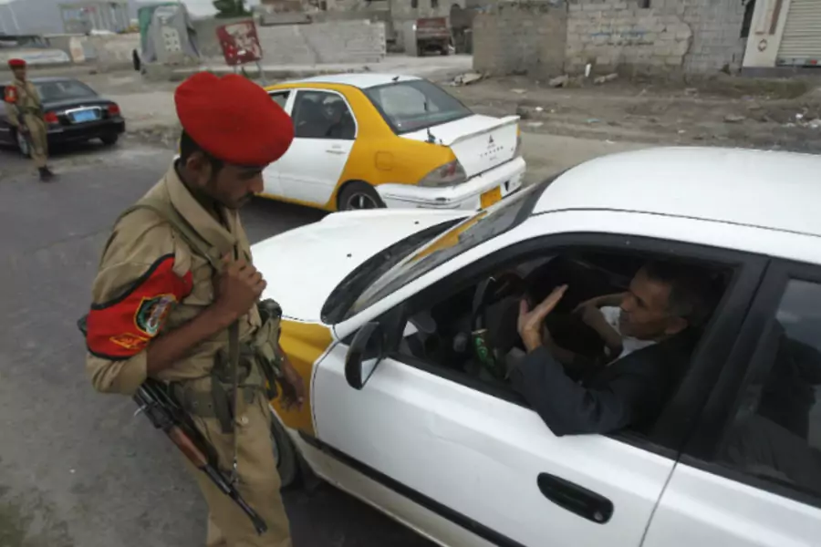 A military police trooper checks a car at a checkpoint in Sanaa