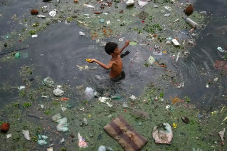 A boy wades through polluted waters in Ahmedabad, India, July 2013 (Courtesy Reuters/Amit Dav).