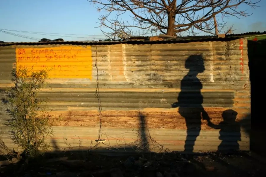 The shadows of a mother and child are cast on a shack in Marikana's Nkaneng township in Rustenburg,South Africa, August 2013 (Courtesy Reuters/Siphiwe Sibeko).