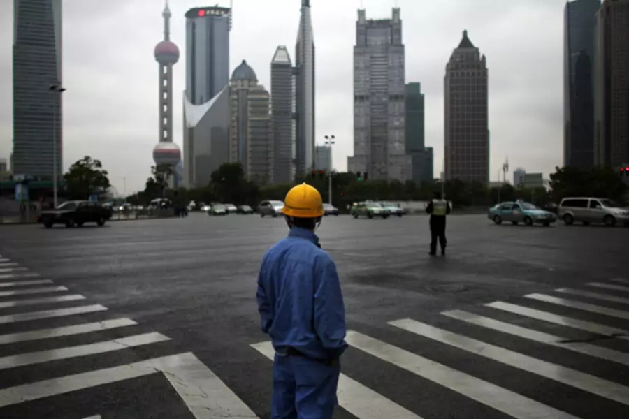 A construction worker looks at the Pudong financial district in Shanghai (Carlos Barria/Courtesy Reuters).