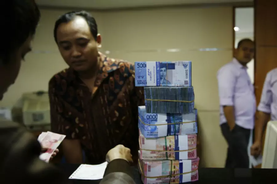 A money changer (facing camera) helps a customer convert Indonesian rupiah in Jakarta on August 20, 2013. Asian emerging market currencies extended losses on Tuesday, with the rupiah hitting a fresh four year low. (Beawiharta Beawiharta/Courtesy Reuters)