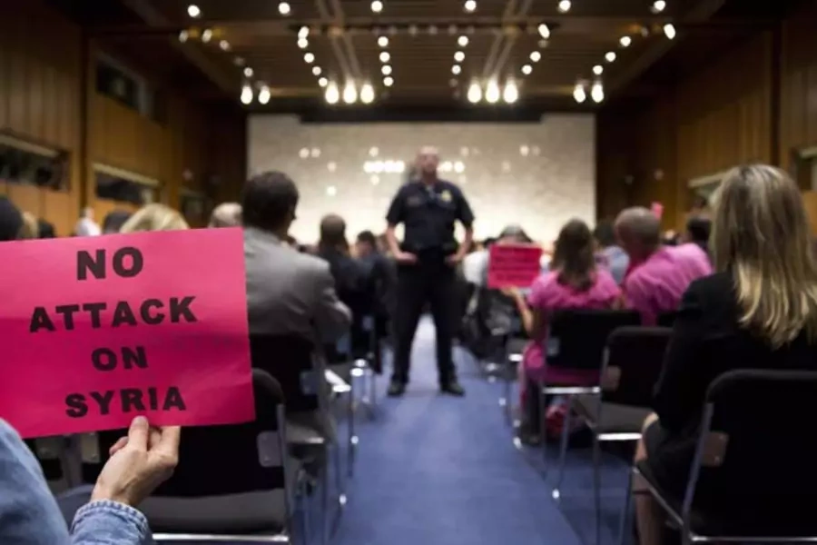 A protester holds up a sign against U.S. action in Syria as Chairman of the Joint Chiefs General Martin E. Dempsey, Secretary ... and Secretary of Defense Chuck Hagel testify before the Senate Foreign Relations Committee (Joshua Roberts/Courtesy Reuters).