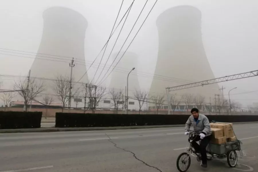 A man cycles past the water-cooling towers of a coal-fired power plant on a hazy day in Beijing on January 22, 2013. (Jason Lee/Courtesy Reuters)