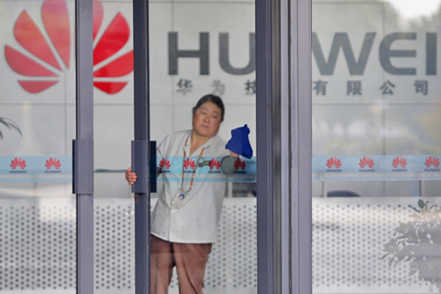 A cleaner wipes the glass door of a Huawei office in Wuhan, Hubei province (Courtesy Reuters).