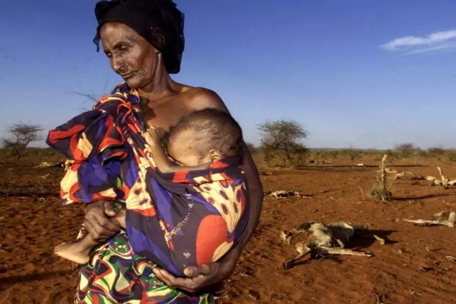 Ruqia Aroo, 80, carries her malnourished grandson near carcasses of dead cattle, Ethiopia, April 2000 (Courtesy Reuters).
