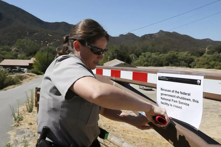 U.S. Park Ranger Melanie Turner posts a sign on the gate of the Paramount Ranch to close the National Park Service site at the Santa Monica Mountains in California (Lucy Nicholson/Courtesy Reuters).